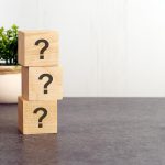 wooden-cubes-with-three-question-marks-gray-background-information-concepts-green-plant-white-background